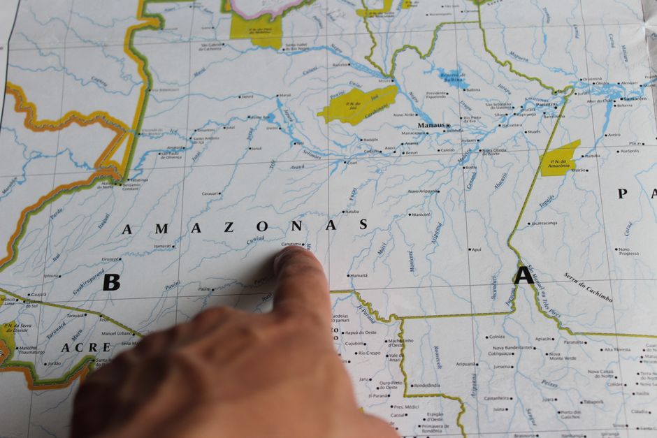 A close-up of a person's hands pointing to a specific location on a digital map displayed on a tablet, representing hyper-local content strategy for SEO.