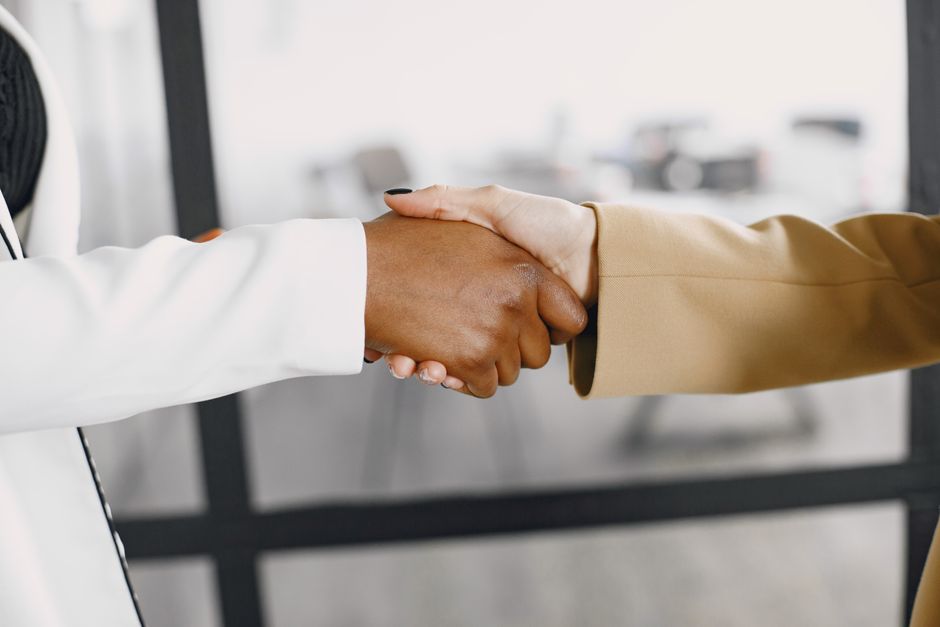 A firm handshake between a real estate agent and a client in a bright, modern office, signifying a successful agreement built on established trust and value.